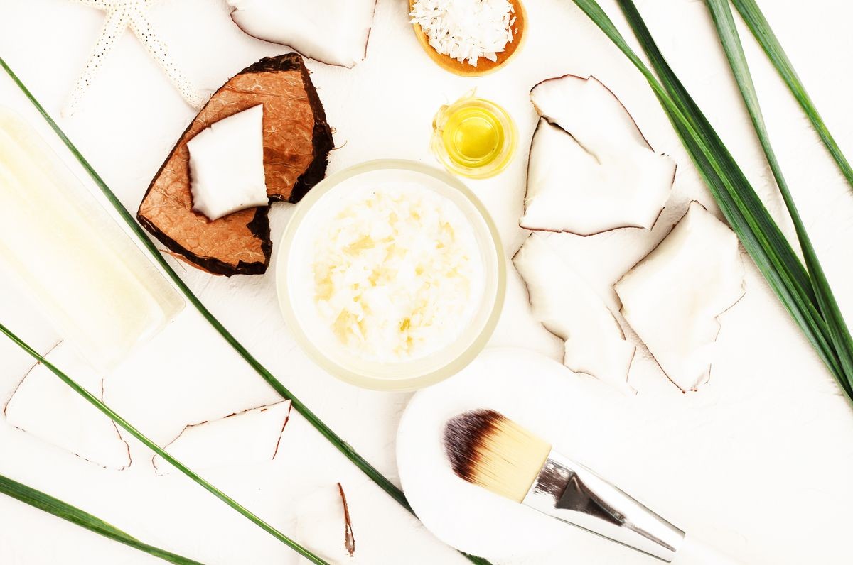 
Coconut cosmetic products, nut pieces white table top view, organic skin care treatment ingdredients